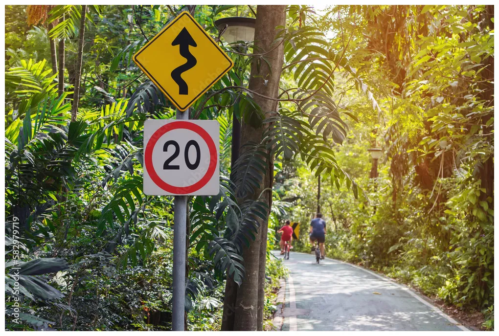 Speed limit road signs and winding road sign with biker on twisty road