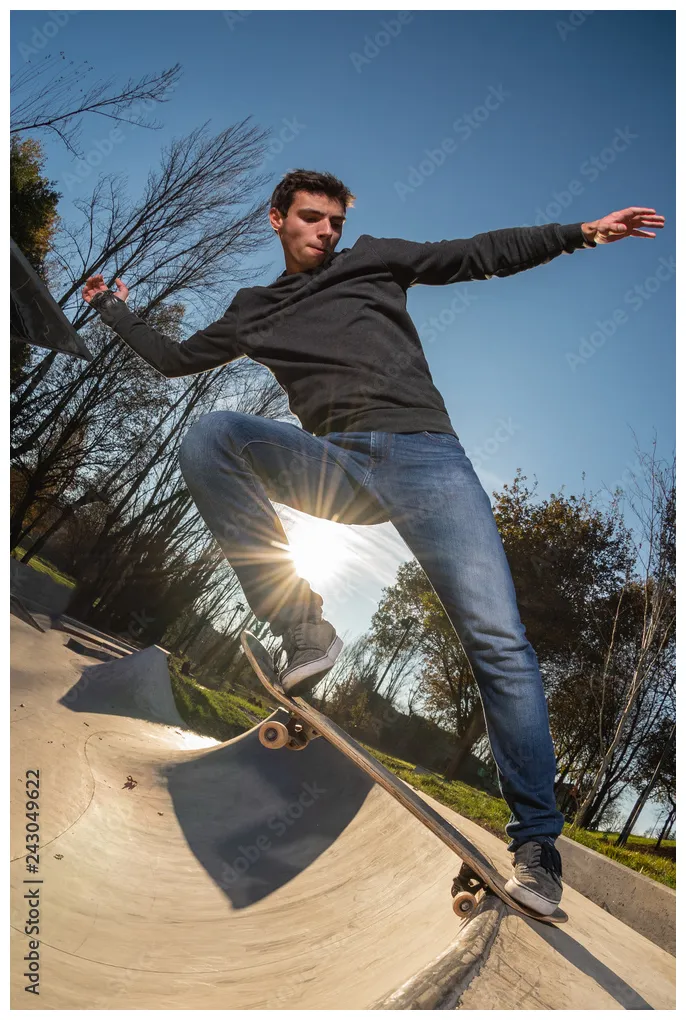 Skateboarder on a tail stall at sunset at the local skatepark. stock