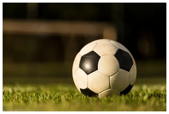 Premium soccer ball on a grass field, under the sunset